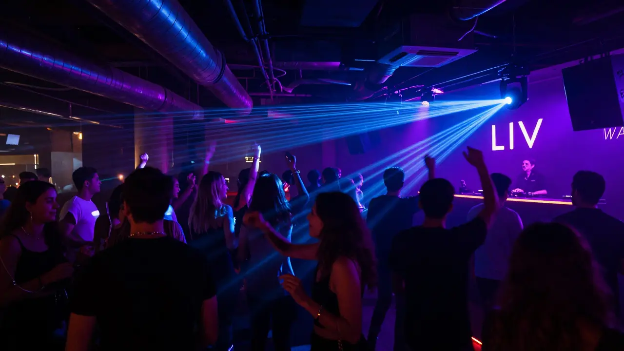 Crowd dancing in a neon-lit underground club with a DJ spinning electronic music.